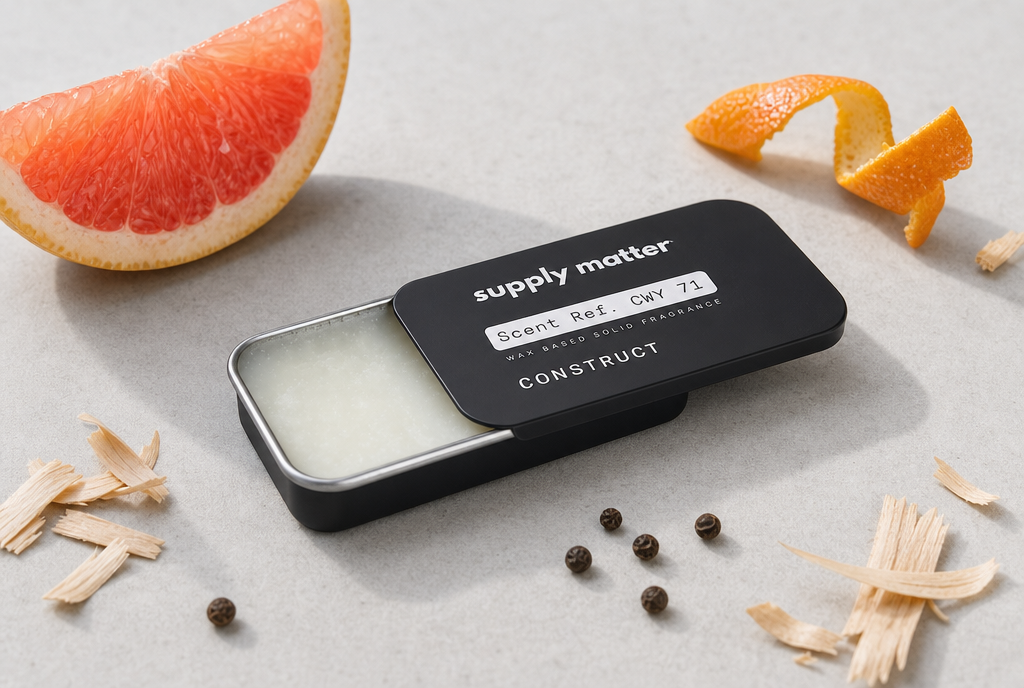 CONSTRUCT solid cologne tin, half open, with grapefruit, orange peel, cedar shavings and black pepper