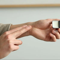Applying solid cologne to the wrist from a pocket-size tin